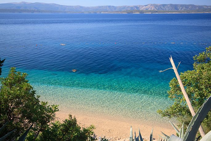 Scenic view of Murvica, a charming coastal village near Bol on the island of Brač, Croatia, featuring crystal-clear waters and traditional stone houses